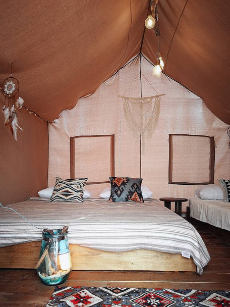 Makuuhuone suuressa teltassa metsässä tai lähellä merta
 - Valokuva, kuva