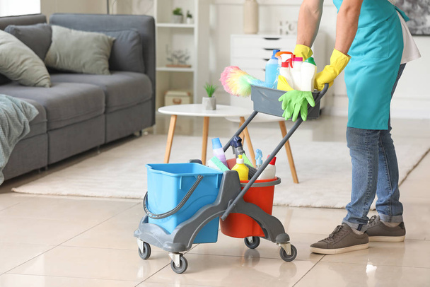 Мужской уборщик с чистящими средствами в квартире
 - Фото, изображение