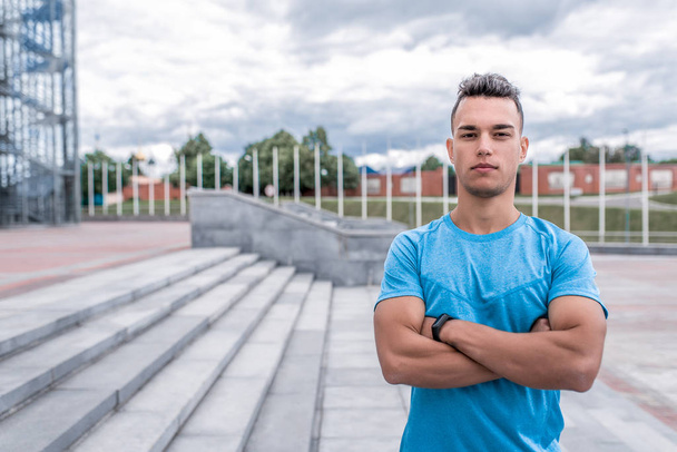 man athlete looks confidently, supervises trainer, teaches, in summer day in city. Active youth lifestyle, fitness workout on street. Free space for text strength motivation. Strong male leader. - Valokuva, kuva