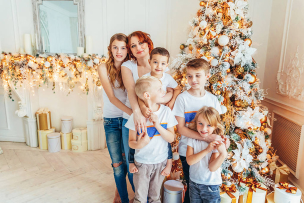 クリスマスツリーを飾る幸せな家族の母親と5人の子供たちは自宅で前夜に。冬の装飾が施された軽部屋の母の娘。クリスマスお祝いのための新年の時間 - 写真・画像