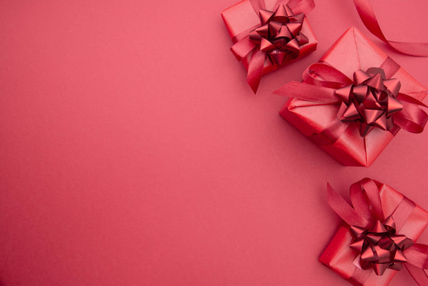 Red gift boxes and ribbon bows, isolated on red background with red bow. Top view. Copy space. Christmas, Party or Valentin's Day concept. - Foto, imagen