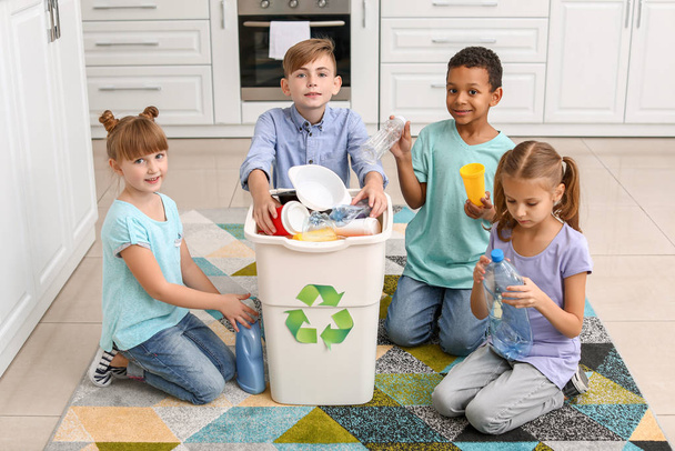 Kleine kinderen en container met afval in de keuken. Concept van recycling - Foto, afbeelding