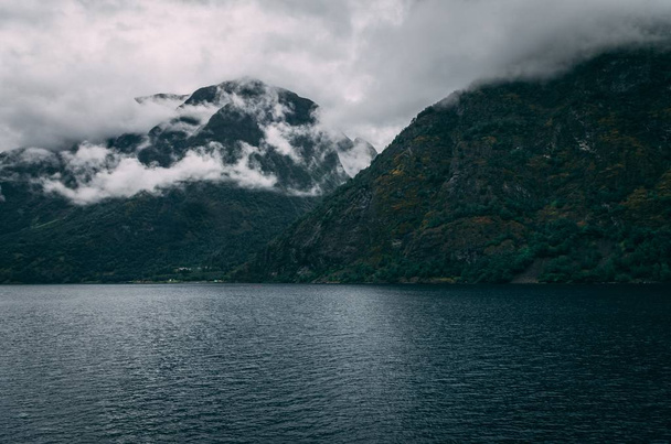 A breathtaking shot of a lake surrounded by the snowy mountains under the foggy sky in Norway - Foto, immagini