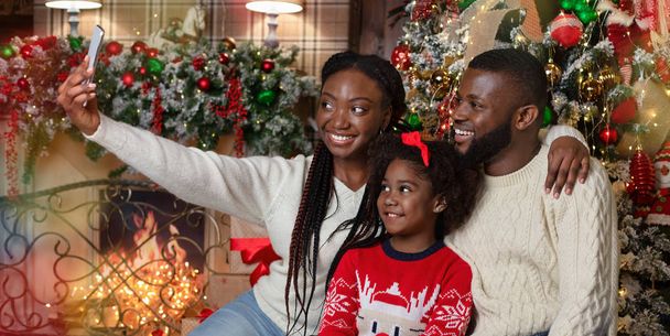 Afro-Amerikaanse familie neemt Kerstmis selfie in ingerichte woonkamer - Foto, afbeelding