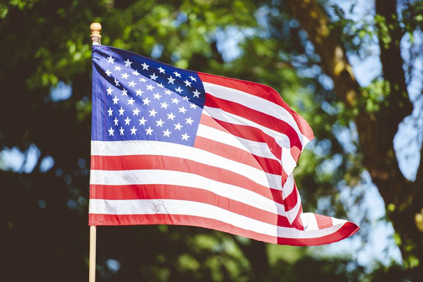 Ένα κοντινό πλάνο της σημαίας των Ηνωμένων Πολιτειών σε ένα κοντάρι με θολή φόντο - Φωτογραφία, εικόνα