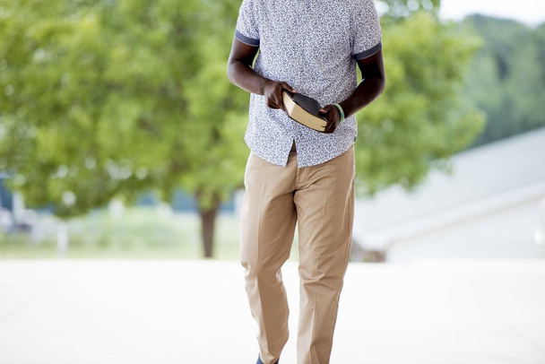A closeup shot of a male walking while holding the bible with a blurred background - Foto, Imagem