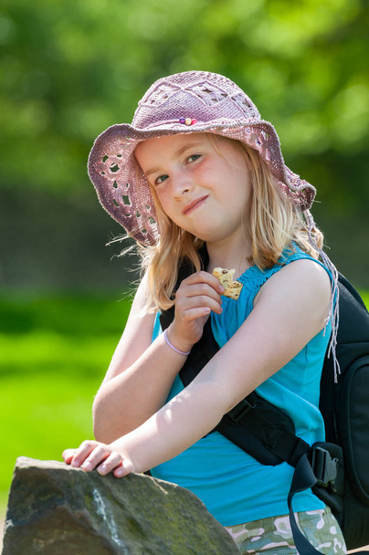 Jolie jeune fille blonde en chapeau violet mangeant une collation
 - Photo, image