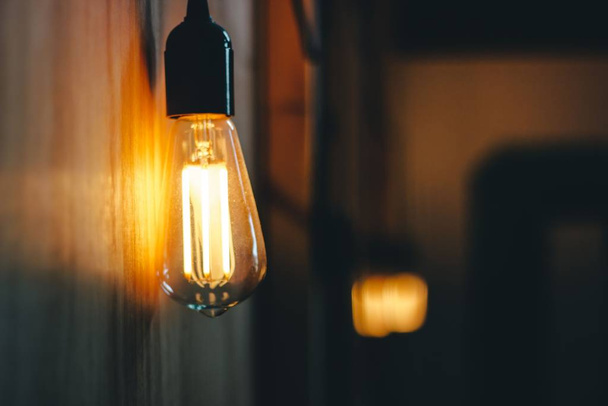 A selective focus shot of a lamp spreading light around in the middle of a room - 写真・画像