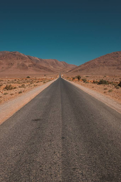 A vertical shot of a road in the middle of the desert and mountains captured in Morocco - Foto, immagini