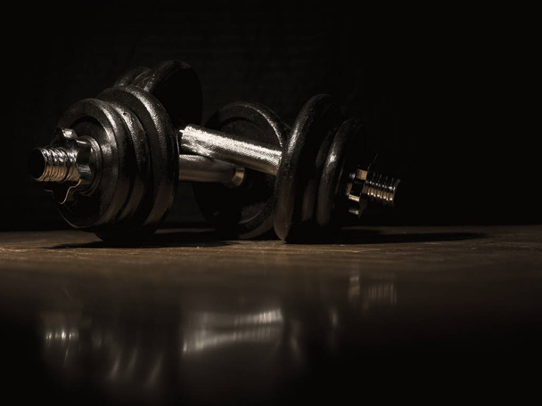 two dumbbells lying on a wooden floor - Photo, image