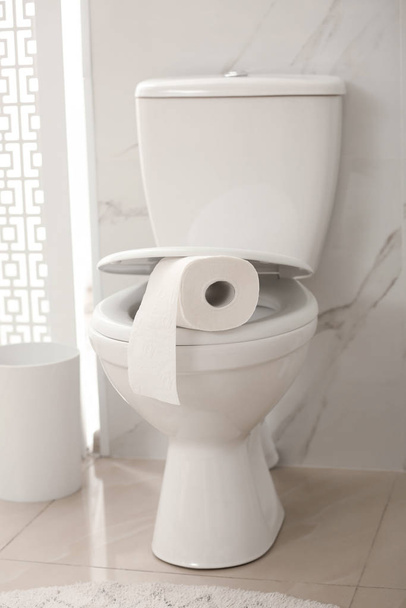 Paper roll on toilet bowl in bathroom - Фото, зображення
