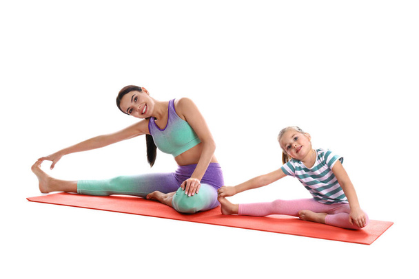 Woman and daughter doing yoga together on white background. Home fitness - Φωτογραφία, εικόνα