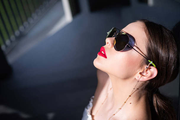 Portrait of a young woman in sunglasses. Close-up portrait of a beautiful charming young attractive lady. Young woman posing. Beautiful young model with big glasses-close up. Dark background. - Foto, afbeelding
