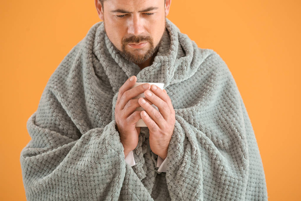 Mies sairas flunssa juo kuumaa teetä värillä taustalla
 - Valokuva, kuva