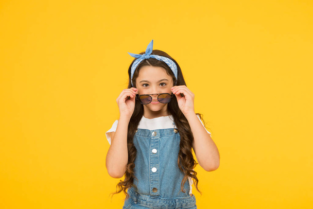 summer look. retro child long hair. small kid vintage sunglasses. Vacation mode on. Little fashionista. Kids boutique. retro girl. Summer fashion concept. cheerful little girl yellow background - Фото, изображение