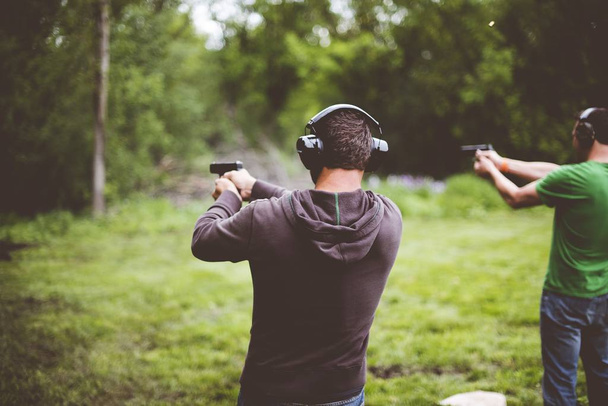 Płytkie ujęcie ludzi strzelających z broni w naturze. - Zdjęcie, obraz