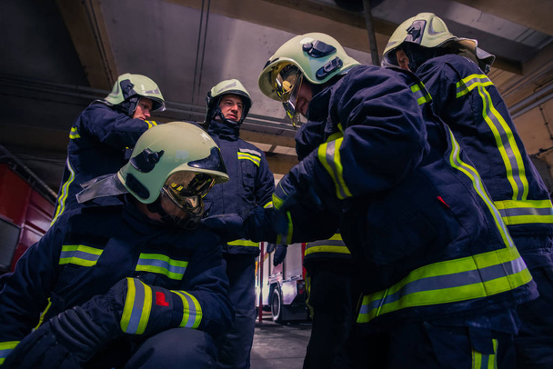 A tűzoltóságon védőegyenruhát viselő tűzoltók csoportjának portréja - Fotó, kép