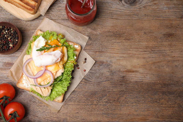 Tasty sandwich with chicken and poached egg on wooden table, flat lay. Space for text - Foto, imagen