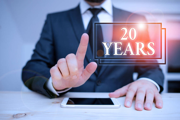 Writing note showing 20 Years. Business photo showcasing Remembering or honoring special day for being 20 years in existence Male human wear formal clothes present use hitech smartphone. - Photo, Image