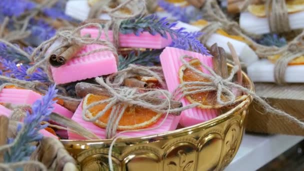 Jabón blanco y rosa bellamente decorado con rodajas de naranja secas, palitos de canela y ramitas de lavanda en el mostrador de la tienda
. - Imágenes, Vídeo