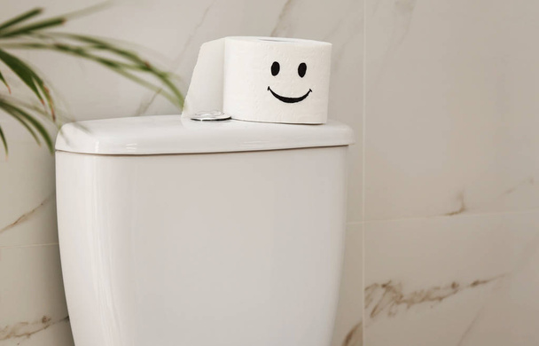 Roll of paper with funny face on toilet bowl in bathroom - Foto, imagen