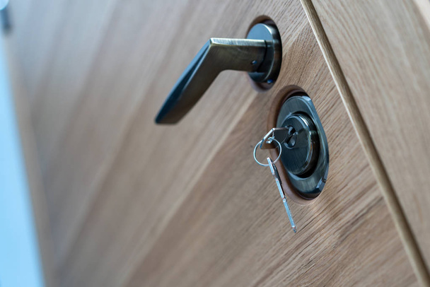 serratura con chiave e maniglia da vicino, bella porta d'ingresso moderna in legno per l'appartamento
 - Foto, immagini