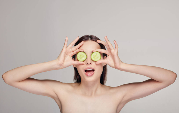 woman making glasses from slices of cucumber with open mouth. Rejuvenation, spa, cosmetics - Photo, image