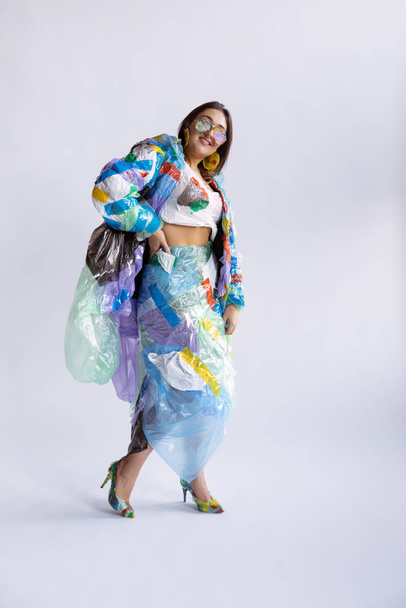 Woman addicted of sales and clothes, wearing plastic, recycling concept - Foto, afbeelding