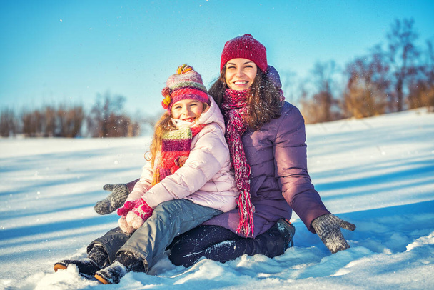 Active mother and daughter playing in winter park - Foto, Imagen