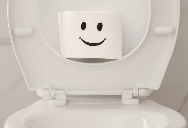 Roll of paper with funny face on toilet bowl in bathroom, closeup - Photo, Image
