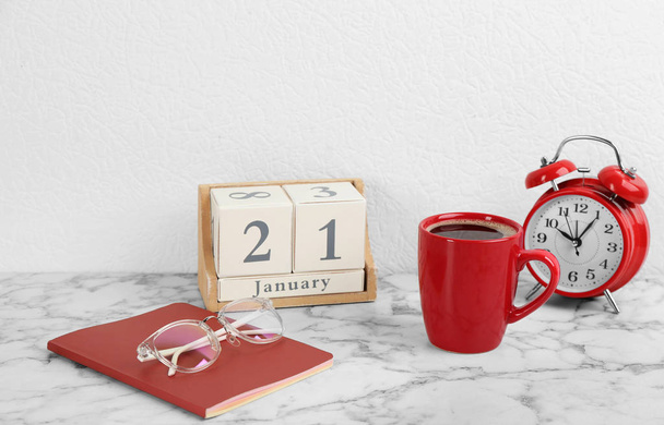 Composition with wooden block calendar and cup of coffee on white marble table - Foto, imagen