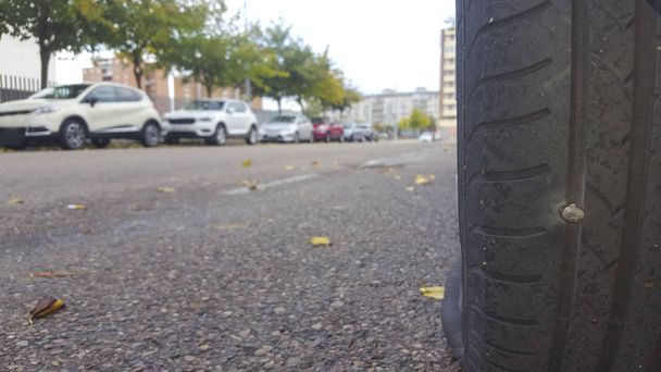 Neumático del coche desinflado porque un clavo está golpeando la goma
 - Foto, imagen