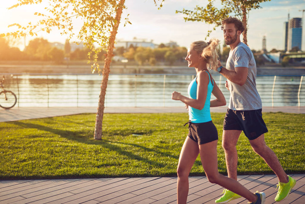 Сучасна жінка і чоловік бігають / займаються спортом в міському середовищі
  - Фото, зображення