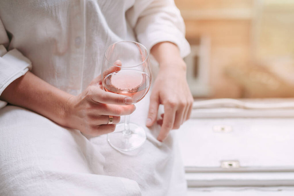 Szklanka różanego wina w dłoni kobiety na widok ulicy. - Zdjęcie, obraz