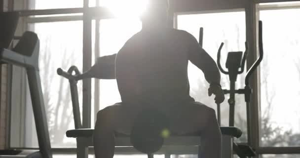 Mężczyzna podnoszenie hantli w siłowni podejmowania ćwiczeń dla biceps - Materiał filmowy, wideo