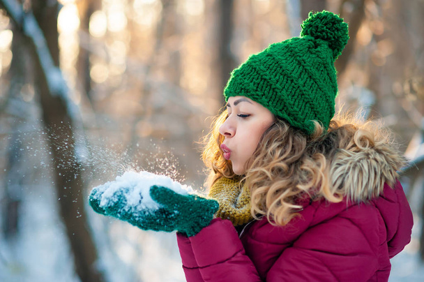 Attractive young girl in winter time outdoor blowing snow - Photo, Image