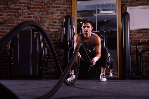 Homem muscular está fazendo exercício de corda de batalha
 - Foto, Imagem
