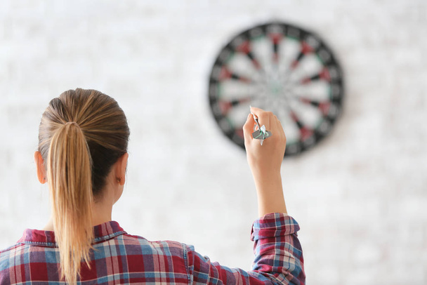 Young woman playing darts indoors - Photo, Image