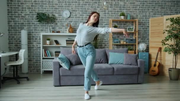 Beautiful young lady dancing at home listening to music alone in living room - Záběry, video