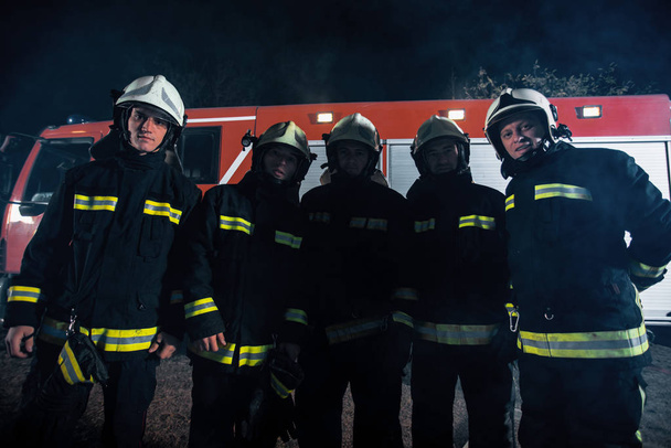 Équipe des pompiers en uniforme avec des casques de protection éteignant un incendie dans la région
 - Photo, image