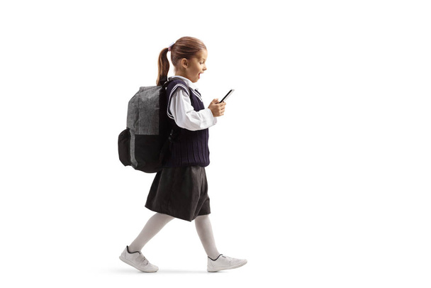 Schoolgirl walking and looking surprised with a mobile phone - Foto, afbeelding