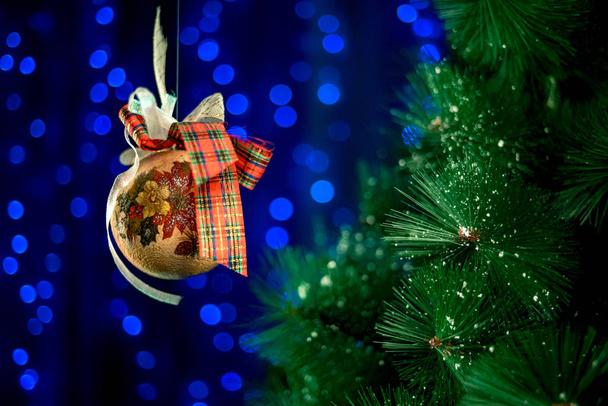 Hausgemachte Weihnachtskugel rollt in der Luft neben dem Weihnachtsbaum.  - Foto, Bild