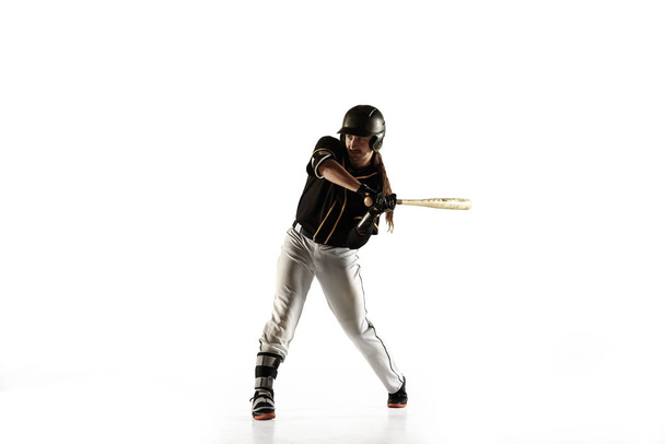 Honkbal speler, werpster in een zwart uniform aan het oefenen op een witte achtergrond. - Foto, afbeelding