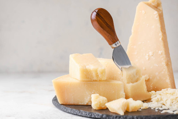 Prato de ardósia com queijo parmesão saboroso no fundo claro
 - Foto, Imagem