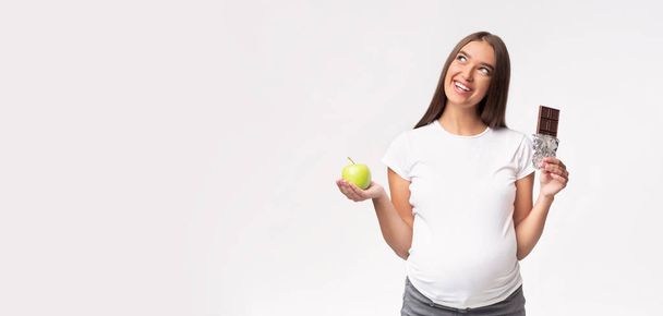 Lady incinta che tiene mela e cioccolato su sfondo grigio, Panorama
 - Foto, immagini