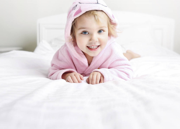 Caucasian child in bathrobe lying in bed,kid hygiena empty space - Fotografie, Obrázek