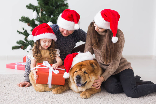Huisdier, vakantie en feestelijk concept - Gezin met hond liggen op de vloer in de buurt van kerstboom. - Foto, afbeelding