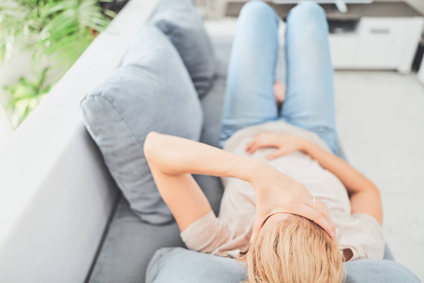 Mujer con problemas de estómago / problemas mientras está acostada en el sofá
. - Foto, Imagen