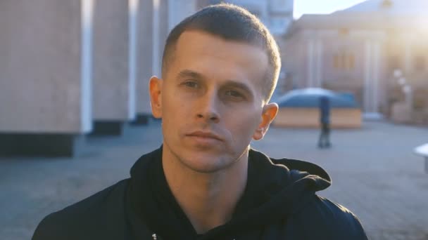 Portrait serious face man looking at camera enjoying in urban city handsome confident lifestyle street urban attractive male in black hoodie close up - Footage, Video
