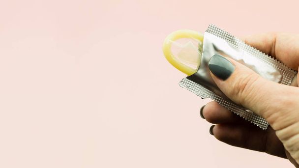 La mano de la mujer sosteniendo el condón abierto en paquete
 - Foto, Imagen